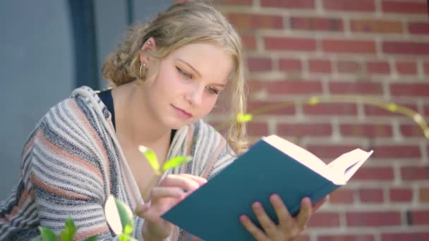 Közelkép Egy Diáklányról Aki Könyvet Olvas Egy Iskola Épülete Előtt — Stock videók