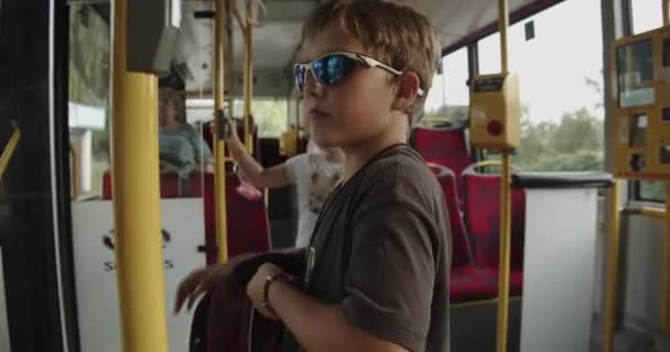 男の子と女の子はバスで学校に行きます少年は彼の学校の袋を閉じます — ストック動画