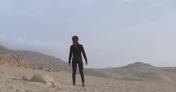 曇った空で砂漠を観察する黒の女性の後ろから撮影された映画 — ストック動画