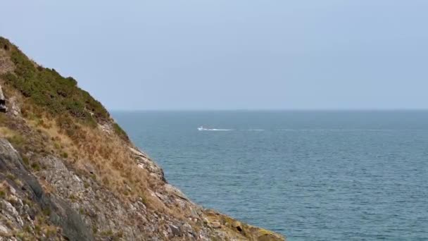 爱尔兰 一艘游艇从Bray Head悬崖上驶过 在平静的蓝色海面上远远地经过 — 图库视频影像