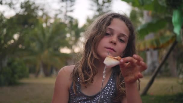 Ένα Κορίτσι Βγάζει Ένα Κομμάτι Ψημένο Ζαχαρωτό Και Τρώει Χαμογελώντας — Αρχείο Βίντεο