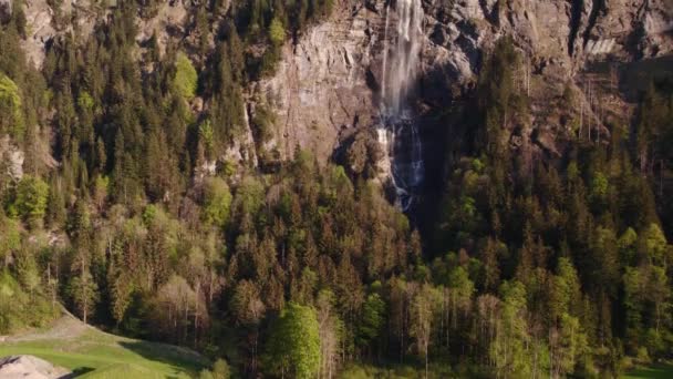 スイスのグリンデルヴァルトにある見事な滝 ファールバッハの素晴らしい景色を眺めながら遠くから上昇する空中ドローン映像 — ストック動画