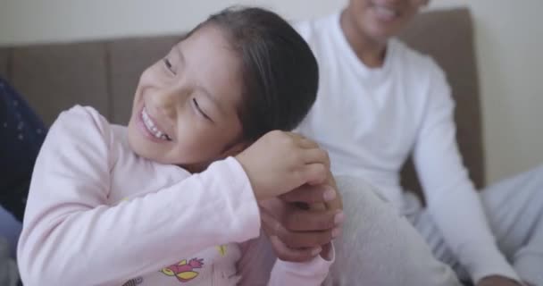 小女孩坐在床上用她父亲的手玩耍的特写镜头 微笑着 慢动作4K — 图库视频影像
