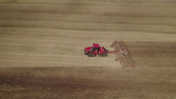 大きな農場フィールドの土壌を再現するために 矢印システムを引っ張っトラック上の大きなトラクターの空中ショット — ストック動画