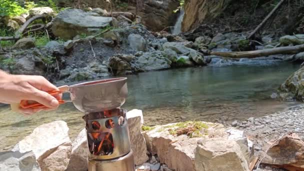 Guy Put Pot Soup Hobo Cooker Stir Waterfall River Background — Stock Video