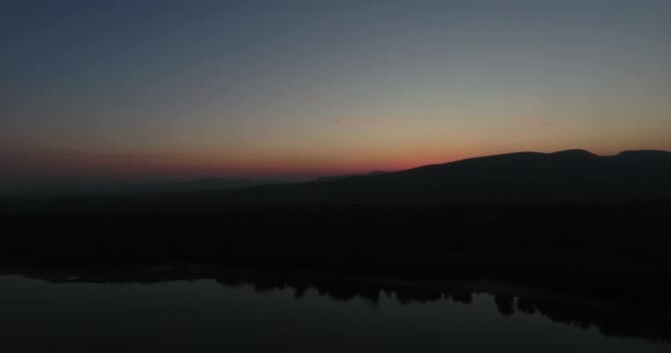 山の上の日没や日の出に向かって水の上を飛ぶ — ストック動画