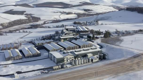 在苏格兰莫雷 冬日的傍晚阳光下 格伦里韦特威士忌酿酒厂被积雪环绕的空中景象 从左到右 — 图库视频影像