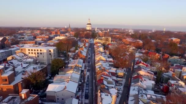 紫の日の出の光の間にメリーランド州の州都の建物や雪のダウンタウンアナポリスメインストリートの空中ショット — ストック動画