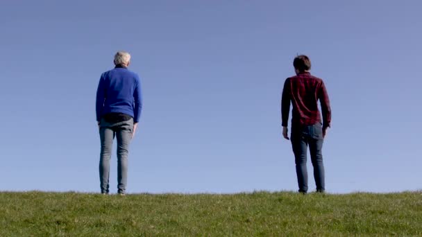 Twee Mannen Staan Groen Gras Met Een Blauwe Achtergrond Horizon — Stockvideo