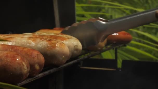 Bbqサニーデーソーセージ焼き料理男性がバーベキューにソーセージを敷く火の生料理 — ストック動画