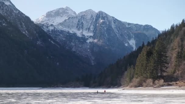 プレディル タルヴィツィオ イタリア雪に覆われた冬のおとぎ話の山の風景の中に凍結された高山湖 人々イタリアの凍った湖でアイススケート — ストック動画