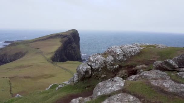 在苏格兰斯凯岛的一个多风多云的日子里 拍摄到了前滨有岩石悬崖峭壁的内斯特角灯塔和背景在大西洋的跟踪镜头 — 图库视频影像