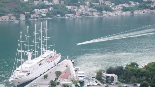 バルカン半島の日没の間にモンテネグロの美しいコトル湾 コトルの旧市街の港に停泊した帆船でコトル湾を航行する船 — ストック動画