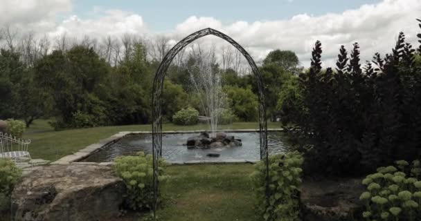 在美丽的阳光明媚 多云的一天 穿过一个金属拱门走向一个美丽的喷泉 背景是斯特拉斯米尔婚礼和活动中心的一片森林 — 图库视频影像
