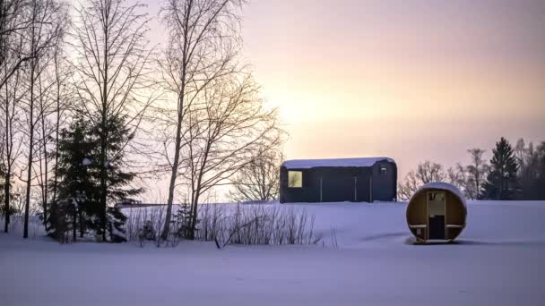 白い冬の風景の中に夕日の間に空を飛ぶ星の時間の経過バレルサウナと木製の小屋 — ストック動画
