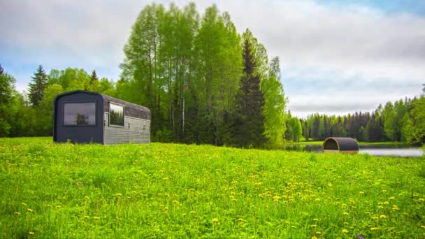 日の出の空に変化する自然と色の芝生のフィールド上の木造住宅のタイムラプスショット 荒野で暗いと青い空に雲を飛んで — ストック動画