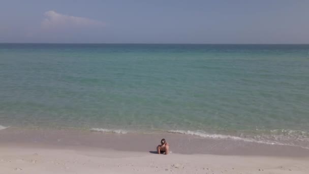 Молодая Женщина Волосами Булочке Лежит Одна Пляже Экспансивным Морем — стоковое видео