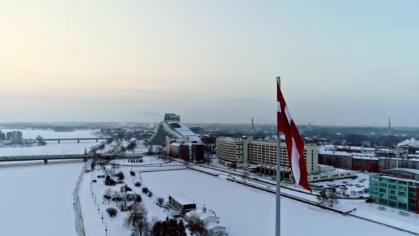 里加寒冷冬日期间拉脱维亚国旗和雪地多加瓦河的空中轨道拍摄 — 图库视频影像