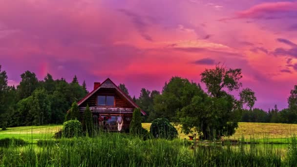 背景にはダイナミックなピンク色の雲が鮮やかに動く牧草地に佇む田舎の小屋のタイムラプス動画 — ストック動画