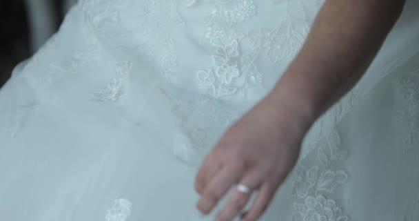 花嫁は椅子に座っている間 彼女の手で彼女のドレスの一部を保持結婚式のガウンに身を包んだ — ストック動画