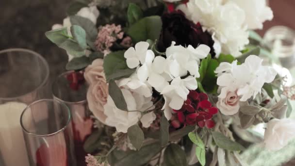 豪華な赤と白の花の花束とキャンドルは 結婚式のディナーのためのドアとしてテーブルの上に設定 — ストック動画
