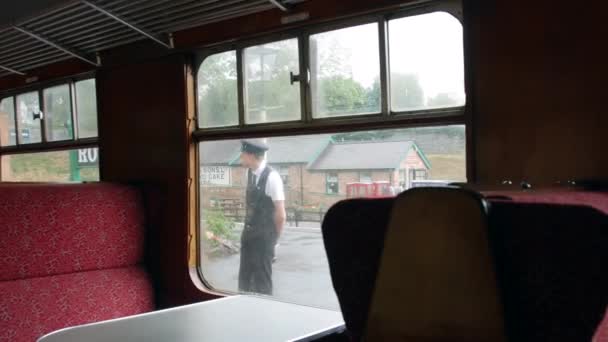 レトロなヴィンテージの列車は イギリスのロスリーにある素晴らしい中央鉄道駅を出発します 指揮者がホームに立っている — ストック動画