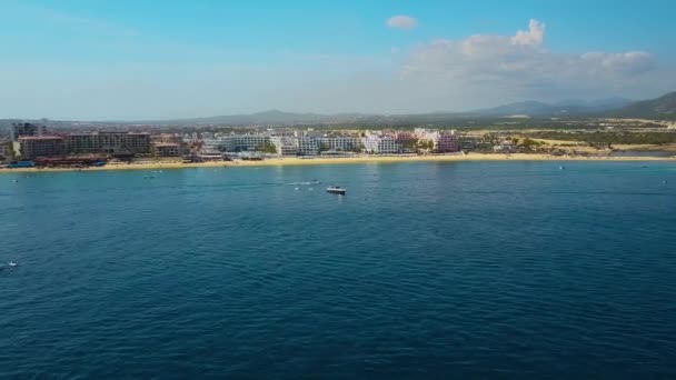 メキシコのカボ ルーカスでリゾートや建物のドローンズームイン映画撮影美しい水とボートで前景の魅惑的なビーチメキシコバハカリフォルニア半島の南端 — ストック動画