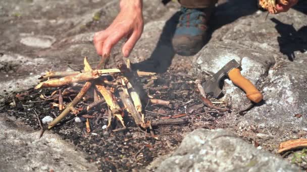 Person Som Lägger Torra Naturliga Grenar Till Nytänd Brasa Stenig — Stockvideo