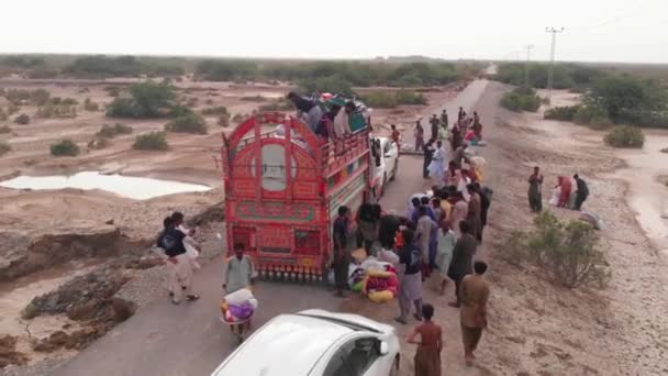 俾路支省偏远地区洪水后提供粮食援助的卡车旁边的人群空中无人机视图 慢动作 — 图库视频影像