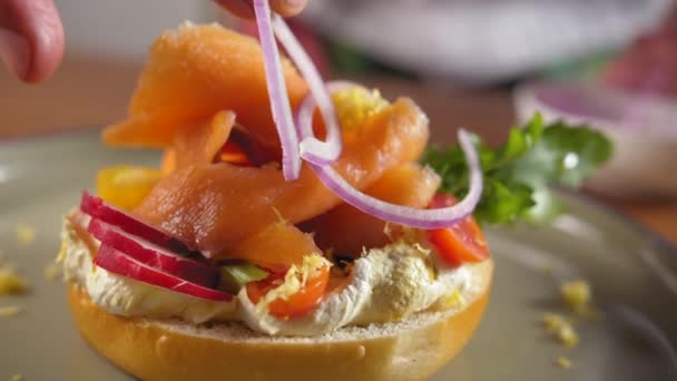 Chef Förbereder Rökt Lax Bagel Placerar Bit Färsk Lök Lax — Stockvideo