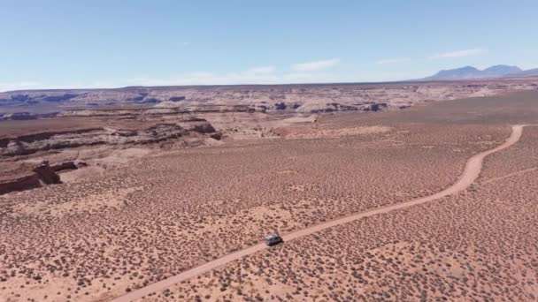 アリゾナ州の広大な赤い砂漠を運転する道路旅行中の空中 キャンパーバン — ストック動画