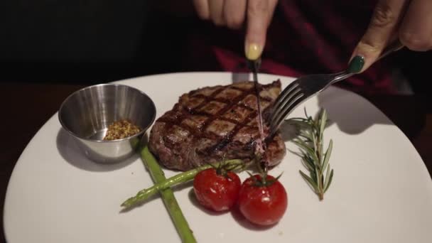 妇女用叉子和小刀在白盘上切牛排 焦点浅薄 — 图库视频影像