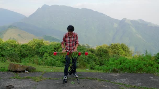 丘陵地帯でキーボードを払っている少年の静的なショット 背景には緑の山々が見える 自然と心安らぐ音楽の良い組み合わせ — ストック動画