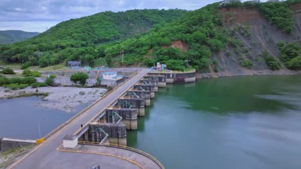 曇りの日の間に背景に空飛ぶプレサ バルデシア ダムと緑の山々 ドミニカ共和国島 — ストック動画