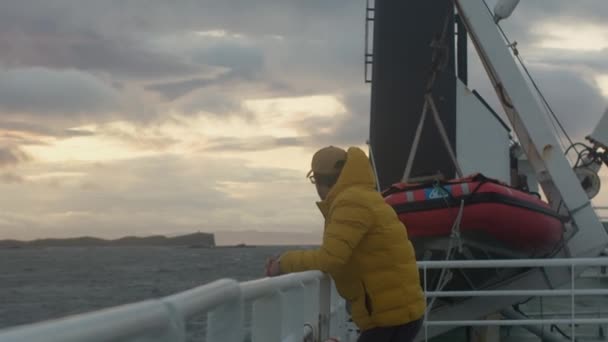 Male Yellow Winter Jacket Leaning Ship Railing Looking Back Coast — Stock Video