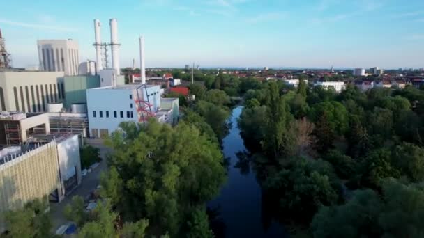 ドイツの都市ブラウンシュヴァイクの大規模なガス火力発電所を背景に澄んだ青い空で穏やかな川のOker上に 高速前方ドローンドーリーショット — ストック動画