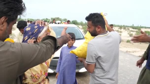 俾路支省抗洪救灾期间 男工向儿童和老年妇女提供黄色食物袋 慢动作 — 图库视频影像
