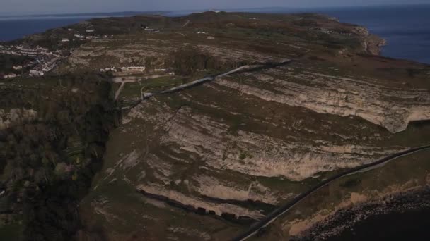 オランダのグレート オーム上空の空中ドローン飛行距離で岩の崖や海を示すウェールズ — ストック動画