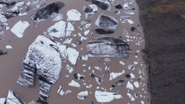 Suuret Poikineet Jäävuoren Palat Kelluvat Ruskeassa Jäätikön Laguunivedessä Ylhäältä Alas — kuvapankkivideo