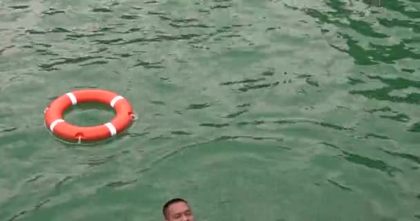 在游泳池里穿着救生衣的男人游向救生衣 穿上救生衣 浮标是指游泳池或海里的安全装置 — 图库视频影像