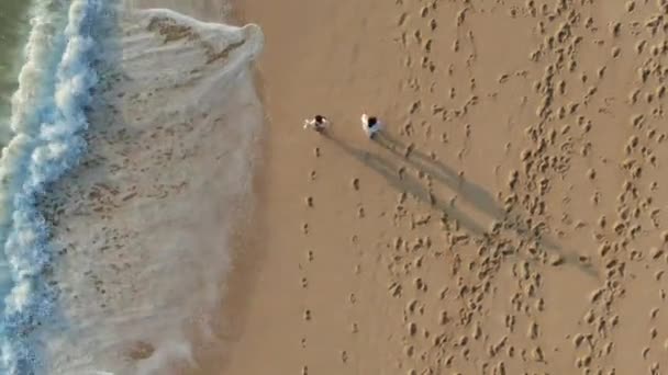 由两个人组成的无人驾驶飞机在巴厘岛的乌鲁瓦乌沙滩上肩并肩漫步 拍摄下的这一航拍镜头中 当海浪接近海岸时 可以看到沙地上的多种脚步声 — 图库视频影像