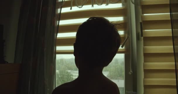 Μια Σιλουέτα Ενός Μικρού Αγοριού Που Κάθεται Στο Παράθυρο Κοιτώντας — Αρχείο Βίντεο