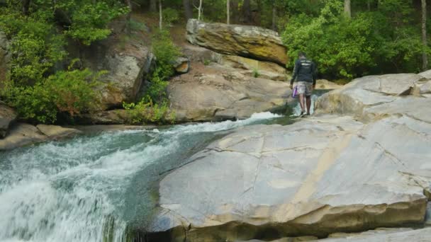 Hombre Busca Algo Una Roca Gigante Mientras Pasa Arroyo Que — Vídeo de stock