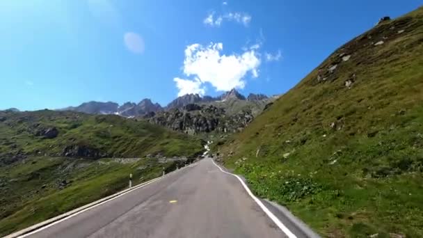 フルカパスのスイスの峠道を車で走っています ダッシュカムビュー ドライバーのビュー いい天気で カーバイの山道でアルプスをドライブしています 山の景色が見えます — ストック動画