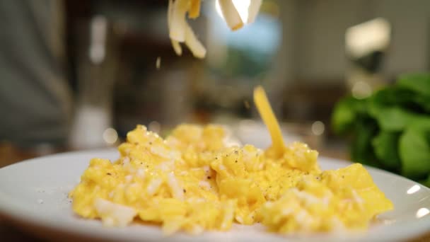 색깔로 잘게찢은 치즈를 가지고 노란색의 신선하고 뜨거운 스크램블드에그 더미에 뿌려진 — 비디오