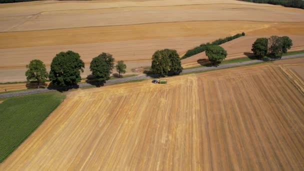 拖拉机载着满载谷物的拖车从收获的田地里驶出 从空中俯瞰着 — 图库视频影像