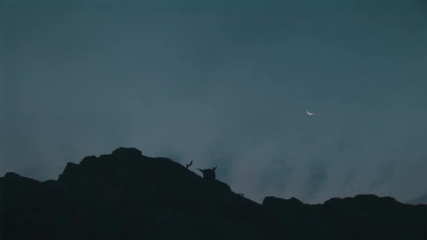在没有阳光的黄昏下爬上悬崖顶上戴着面具的人的轮廓 — 图库视频影像