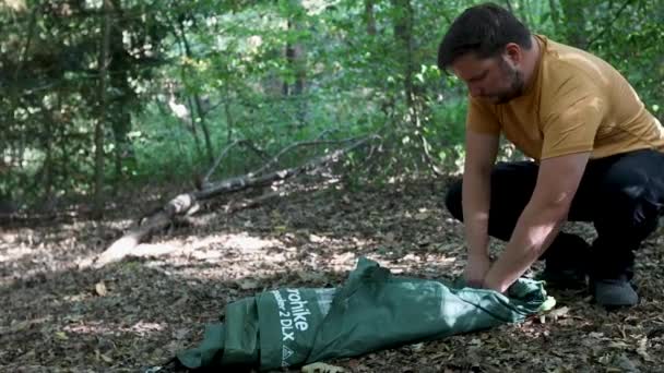 森の中でテントの布を転がす男ビューでズーム — ストック動画