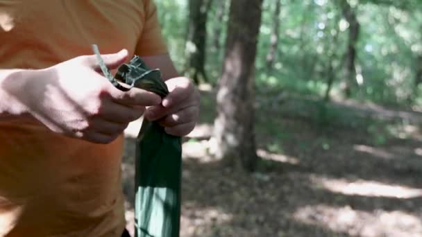 森の中でキャンプした後にテントの部品の小さな袋を結ぶ男は ビューを閉じます — ストック動画