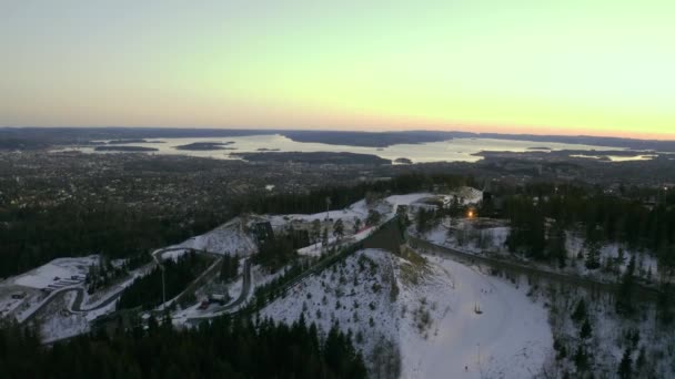 オスロ市内ドローンプッシュイン Vinterpark Winterpark Tryvann過去のスキージャンプでサンセットHolmenkolen北欧クロスカントリースキー — ストック動画